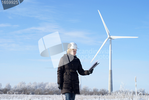 Image of engineer or architect with white safety hat and wind turbines on