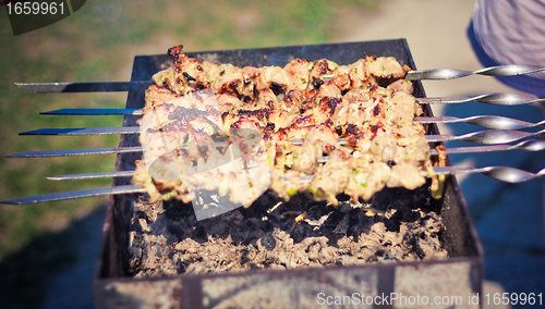 Image of shish kebab in process of cooking on open fire outdoors