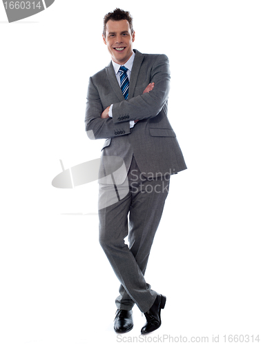 Image of Cheerful young businessman leans against wall
