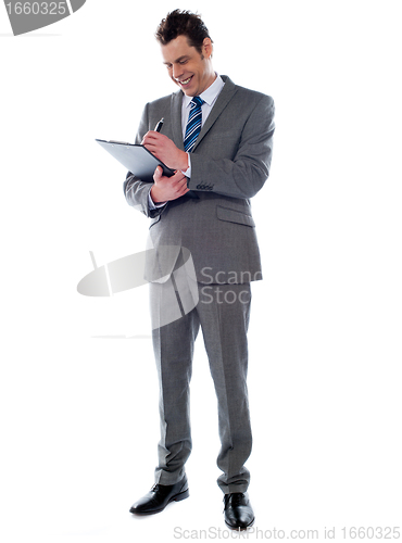 Image of Successful businessman writing notes on clipboard