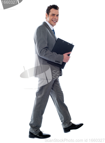 Image of Businessman holding documents and walking