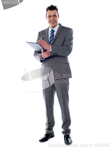 Image of Smiling businessman writing on clipboard