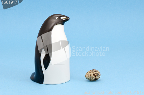 Image of penguin bird sculpture and egg isolated on blue 