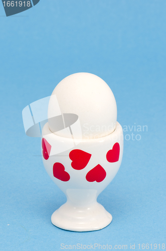 Image of white egg in special cup eating on blue background 