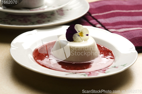 Image of Vanilla panna cotta with berry sauce and spring flower