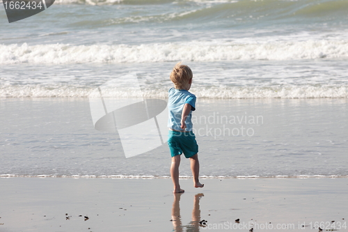 Image of young child walking on the sand to the waves