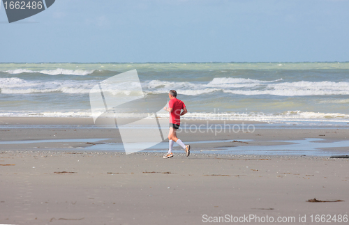 Image of man running on the beach sunny summer
