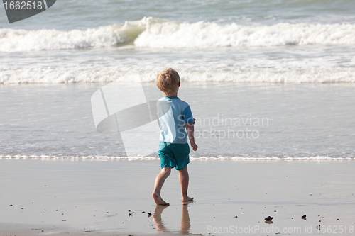 Image of young child walking on the sand to the waves