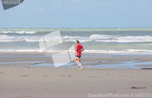 Image of man running on the beach sunny summer