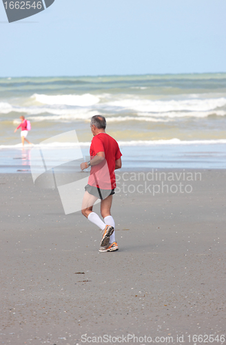 Image of man running on the beach sunny summer