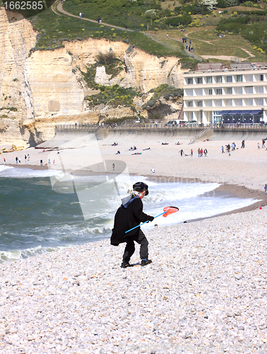 Image of a young child dressed as a fisherman plays on the beach