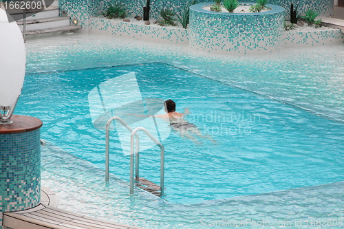 Image of Man swimming in blue water of the pool