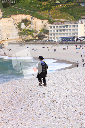 Image of a young child dressed as a fisherman plays on the beach