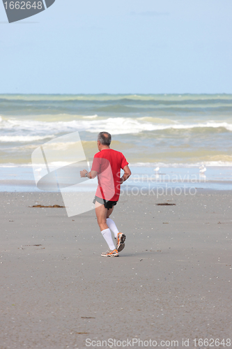 Image of man running on the beach sunny summer