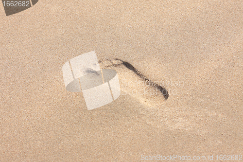 Image of trace of a child's foot on the sand of the beach