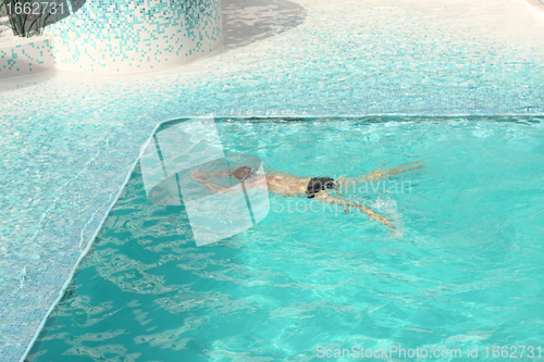 Image of Man swimming in blue water of the pool