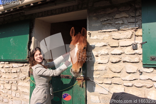 Image of pretty young woman giving food to horses