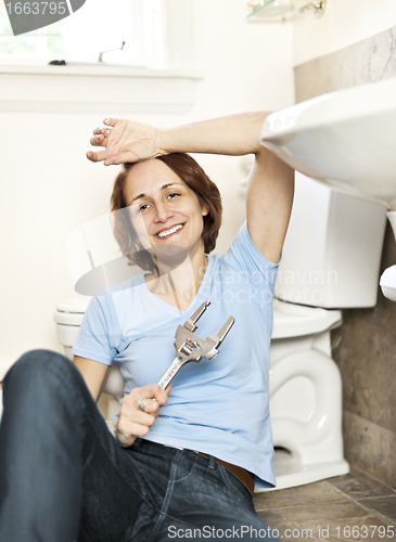 Image of Woman fixing plumbing