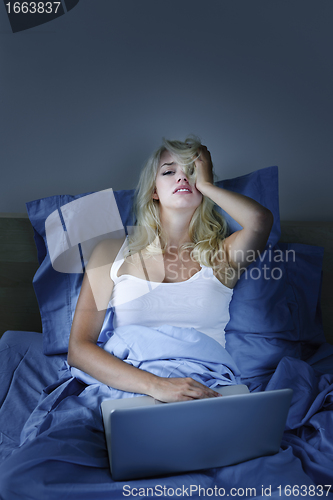 Image of Upset woman with laptop computer in bed