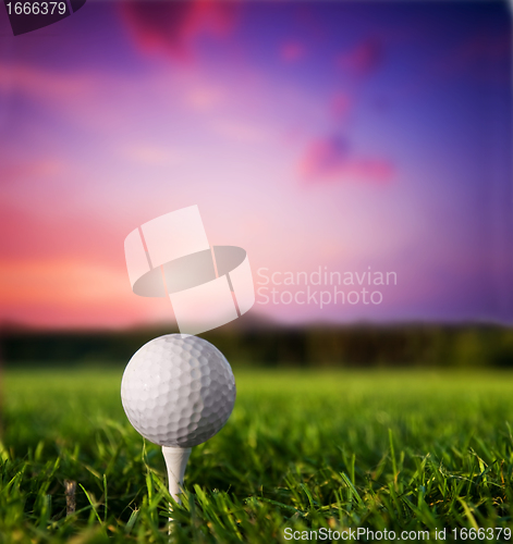 Image of Golf ball on tee at sunset