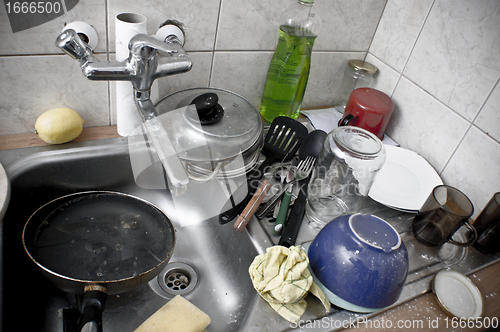 Image of Pile of dirty dishes in the metal sink