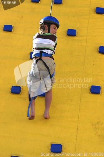 Image of A child abseilling down a climbing wall