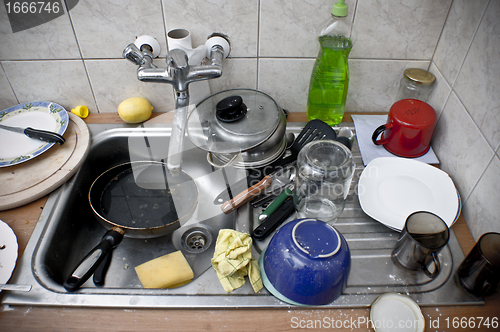 Image of Pile of dirty dishes in the metal sink