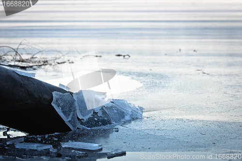 Image of Sewer pipe frozen into water at winter