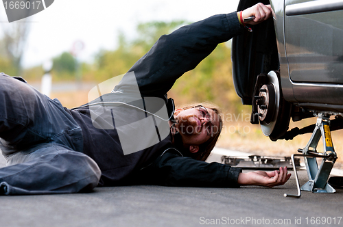 Image of Handsome young man repairing car