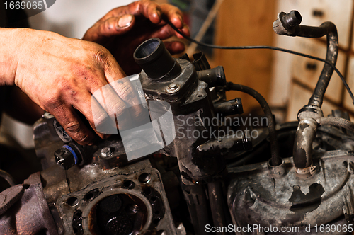Image of Hands of a worker repairing broken engine