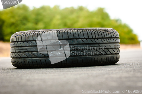 Image of Abandoned car tyre on the road with green background