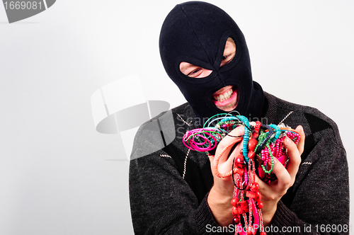 Image of Thief in mask holding expensive goods