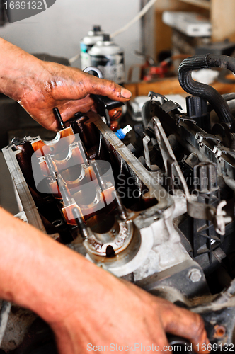 Image of Hands of a worker repairing broken engine