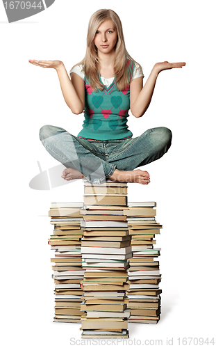 Image of woman in lotus pose balancing on pile of books