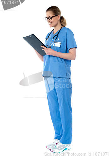 Image of Female surgeon with stethoscope, reading report