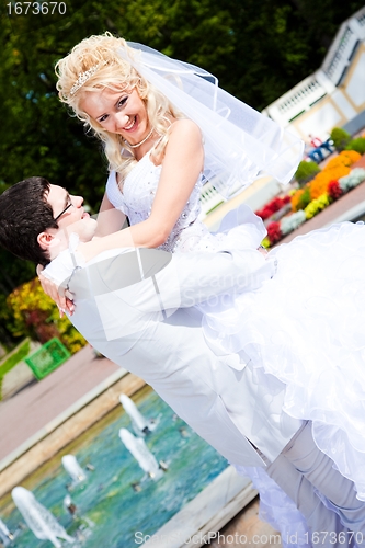 Image of happy groom and bride in a sunny summer park