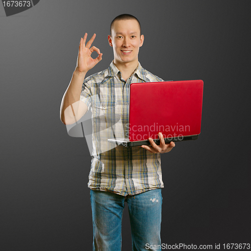 Image of asian male with laptop in his hands shows OK