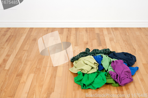 Image of Pile of colorful clothes on the wooden floor