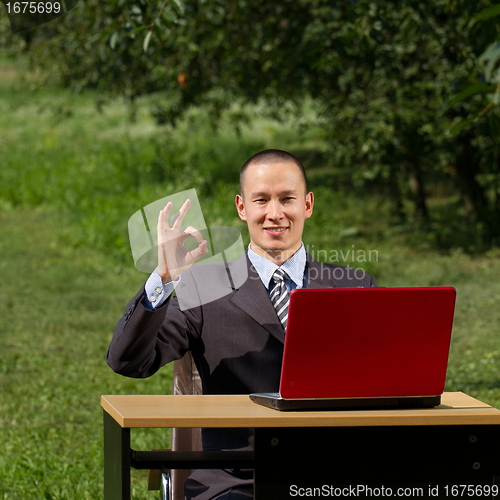 Image of man with red laptop working outdoors