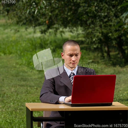 Image of man with red laptop working outdoors