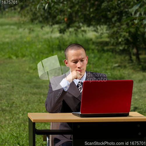 Image of man with red laptop working outdoors