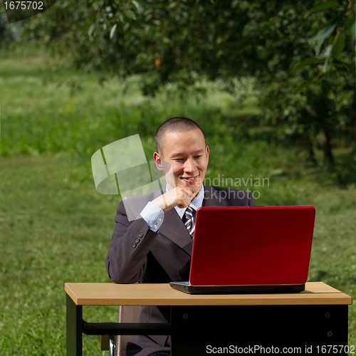 Image of man with red laptop working outdoors