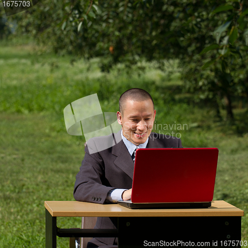 Image of man with red laptop working outdoors