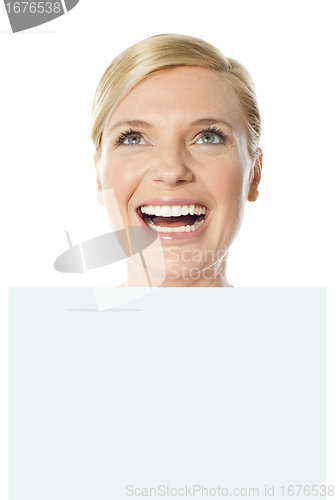Image of Thoughtful smiling woman holding whiteboard