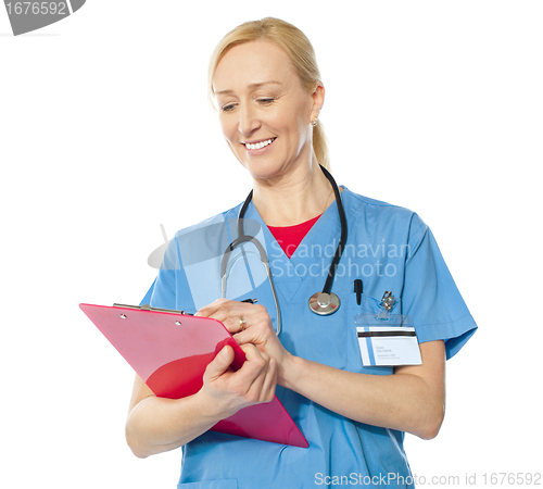 Image of Portrait of happy senior doctor writing on clipboard