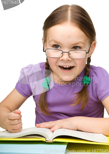 Image of Cute little girl hits a book with fist