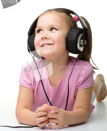Image of Cute little girl enjoying music using headphones