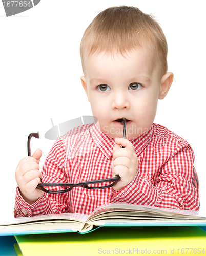 Image of Little child play with book and glasses