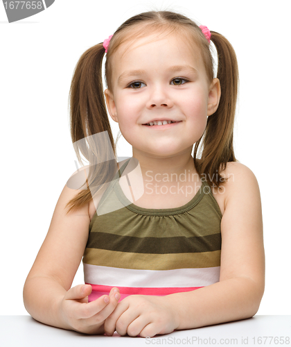 Image of Happy little girl sits at a table and smile