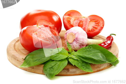 Image of Ripe tomatoes, garlic and basil on a wooden board. 